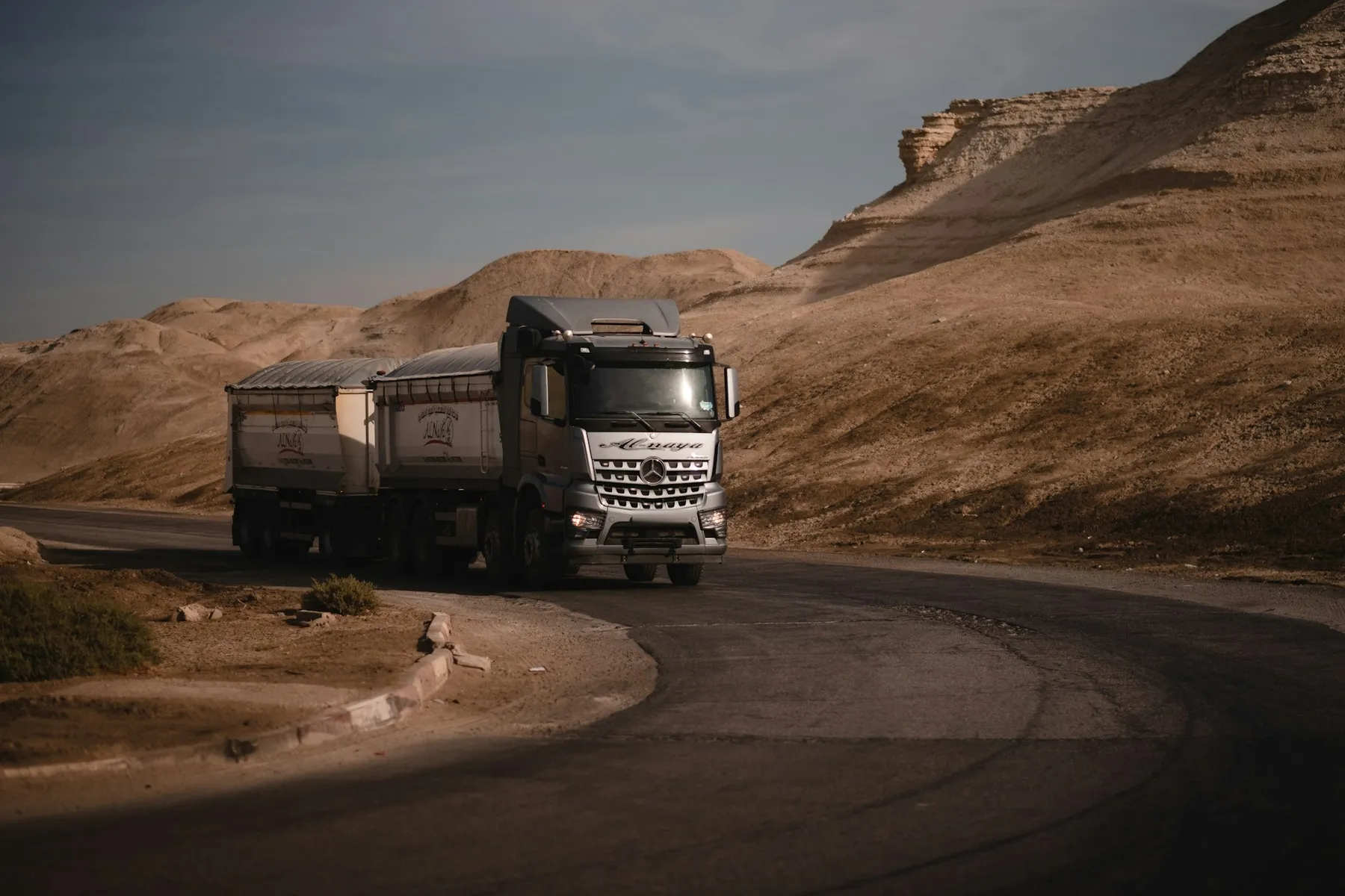 Heavy truck hauling two loaded trailers on a desert road
