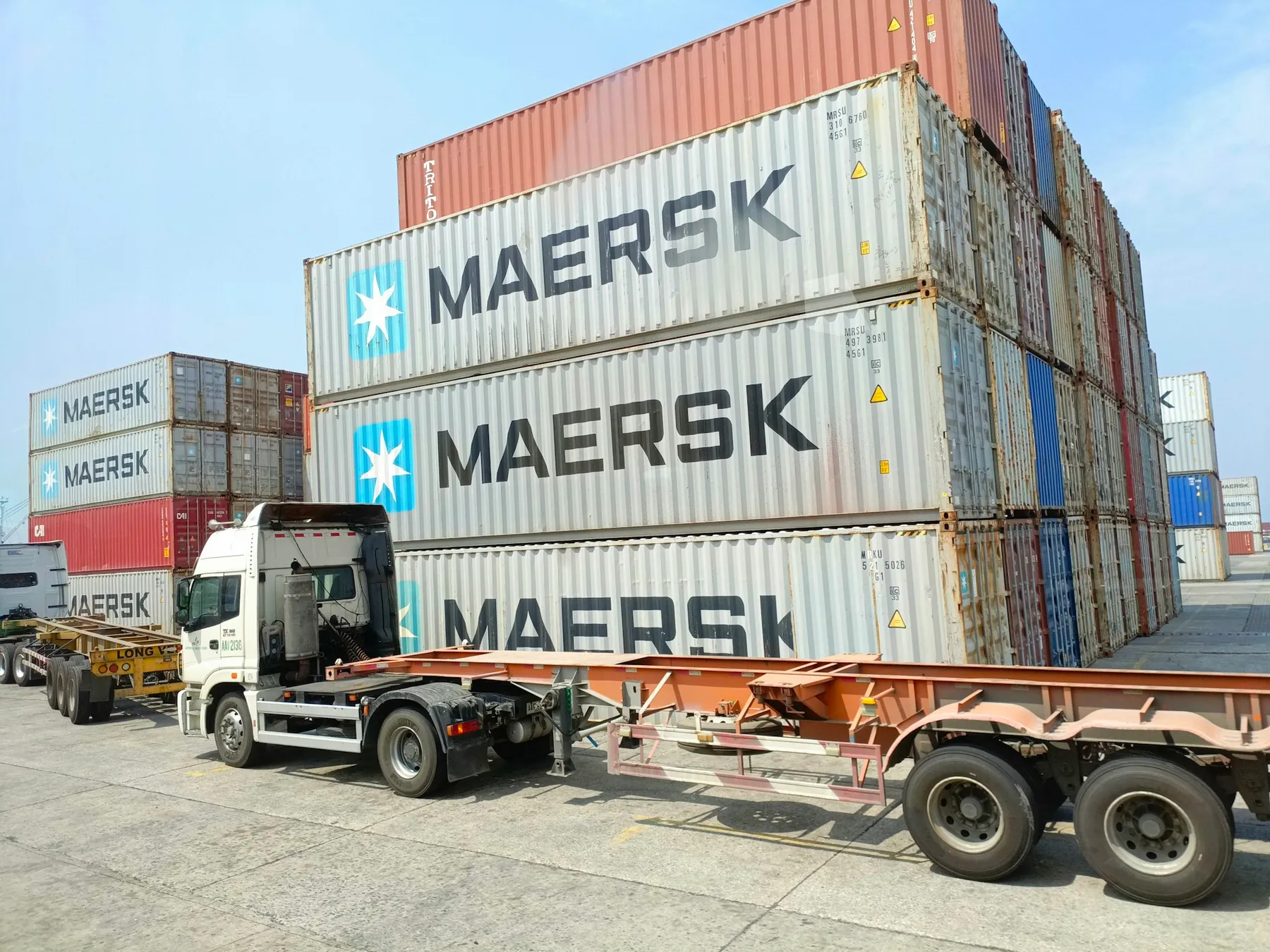 Truck parked beside stacked shipping containers at a port