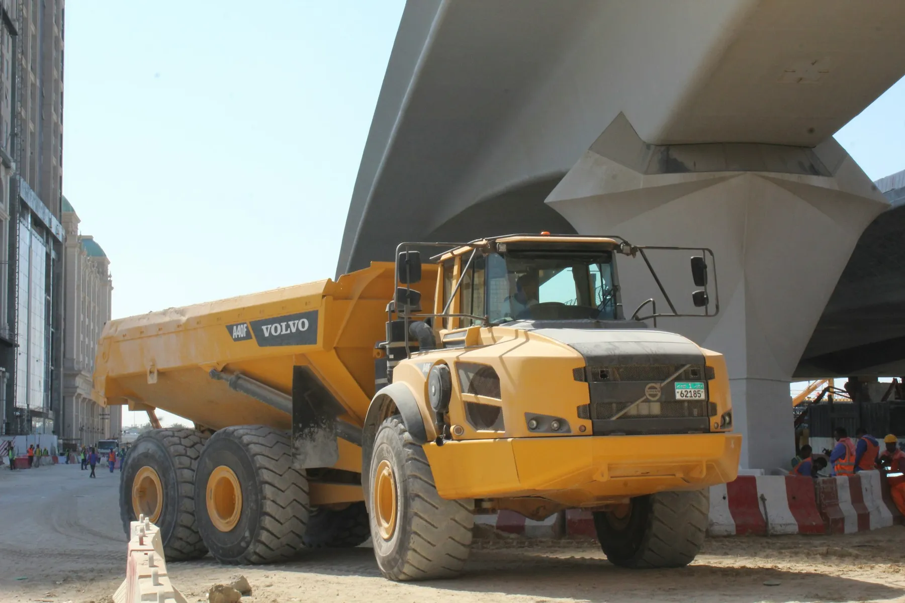 Heavy articulated dump truck working beneath a highway flyover